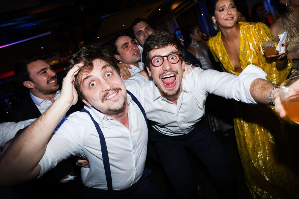 Party guests dancing and having fun in a dark venue with colorful lighting effects.