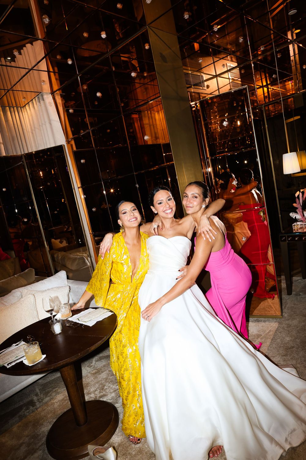 Wedding celebration showing guests in colorful attire dancing and celebrating at an indoor venue.