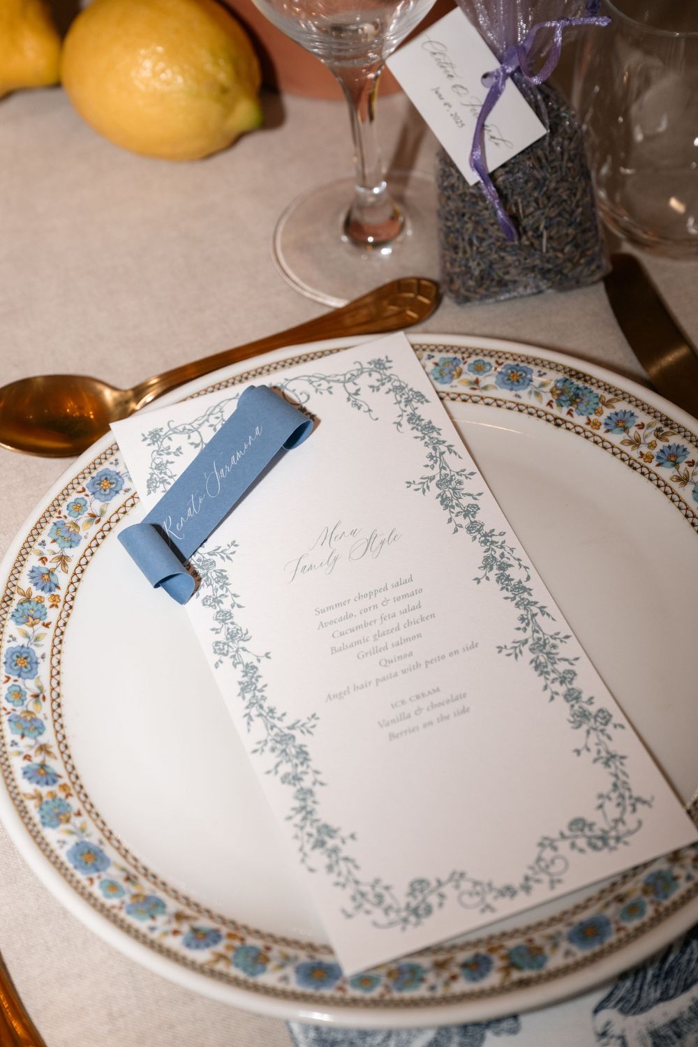 Ornate china plates with blue and silver floral borders displayed alongside elegant menu cards at place settings.