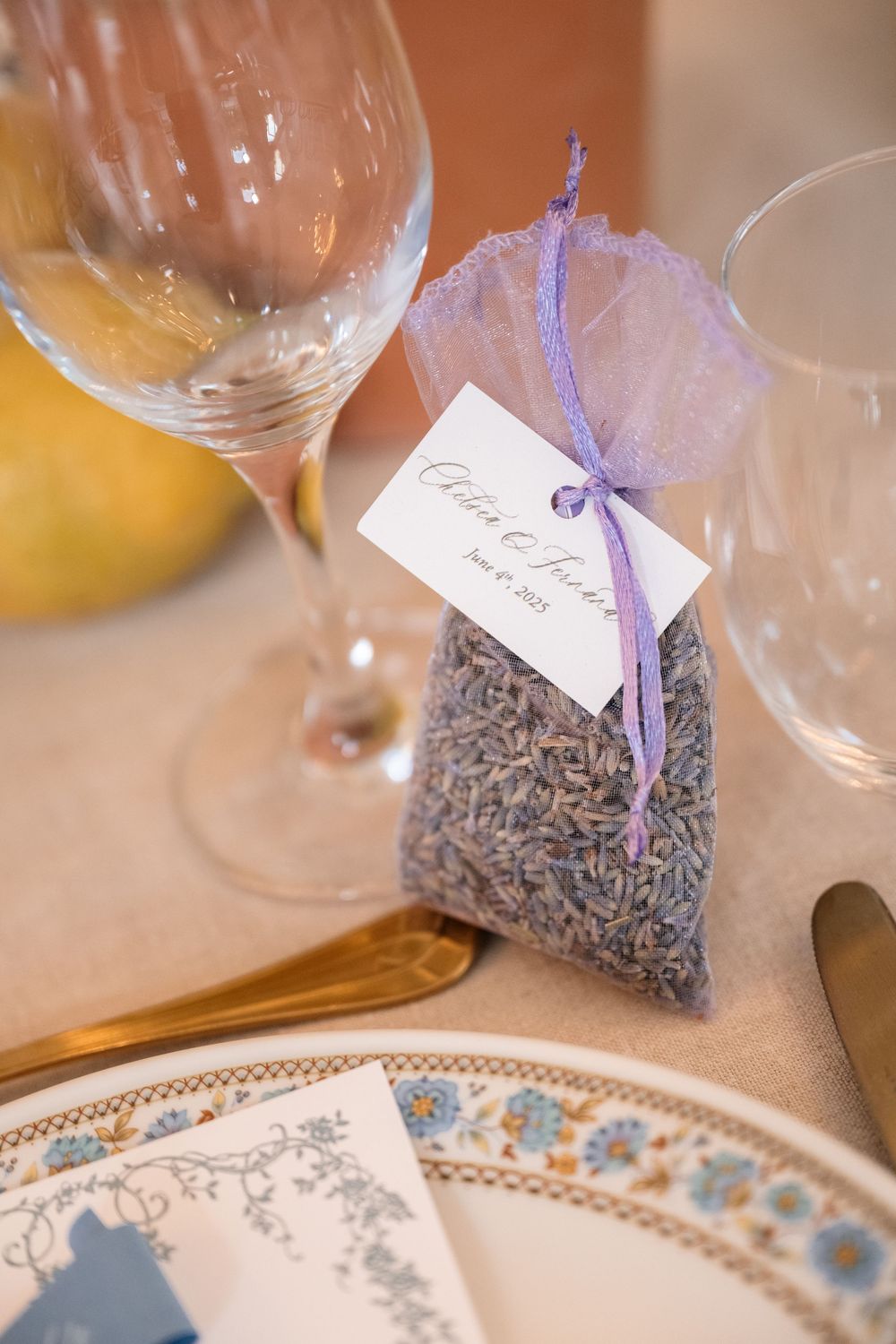 Small lavender sachet wedding favors with name tags displayed next to decorative place settings.