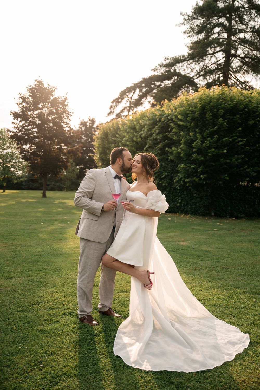 A couple dances and twirls on a sunlit lawn during golden hour at their wedding celebration.