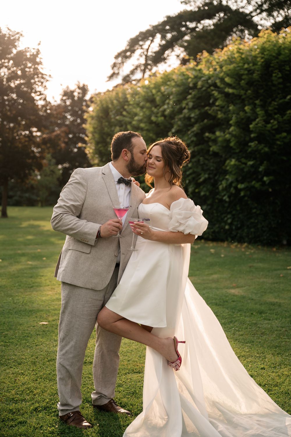 Couple toasting with champagne glasses during sunset in a garden setting.