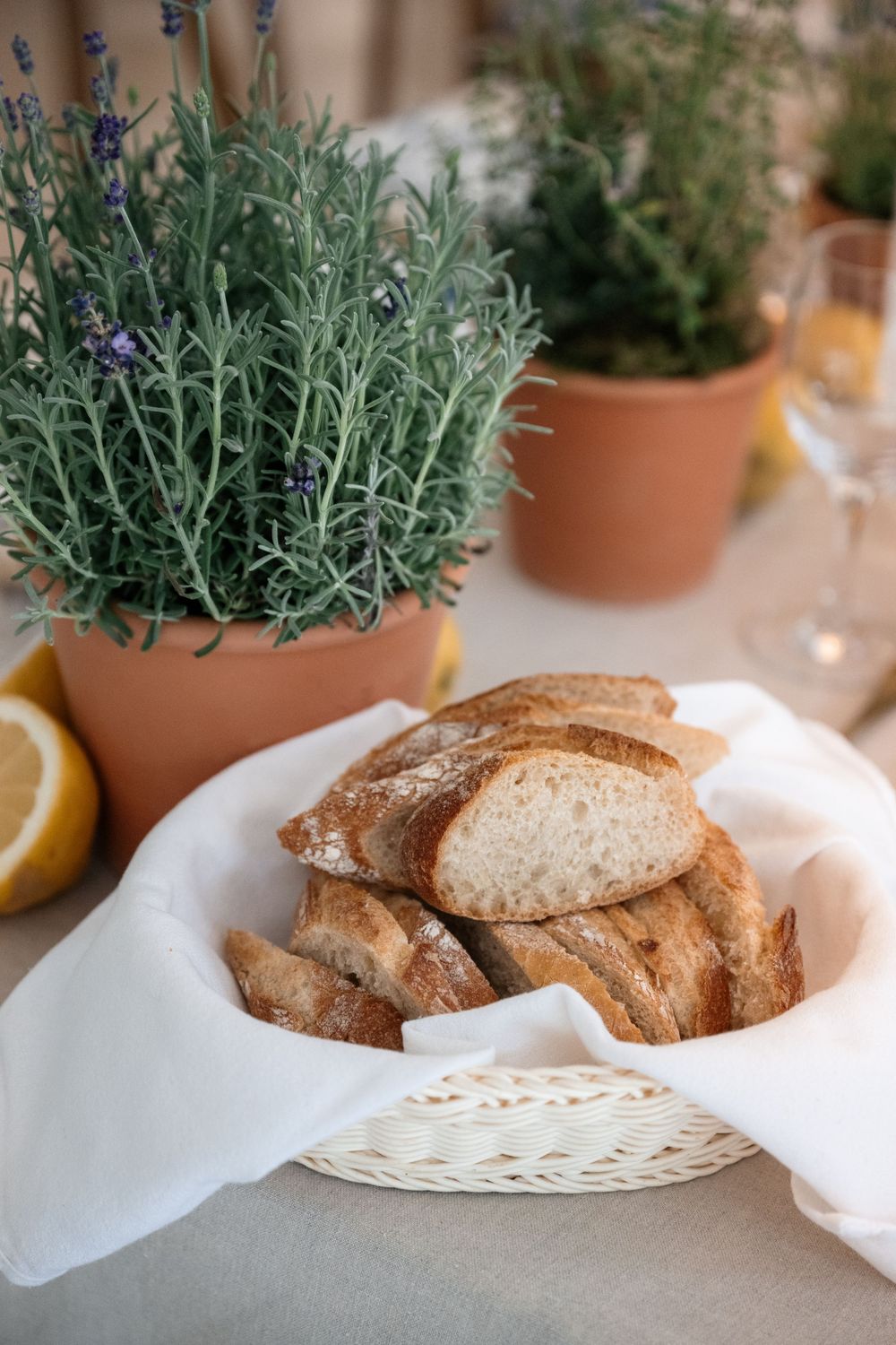 Fresh rustic bread slices on white plates with potted lavender plants as table decoration.