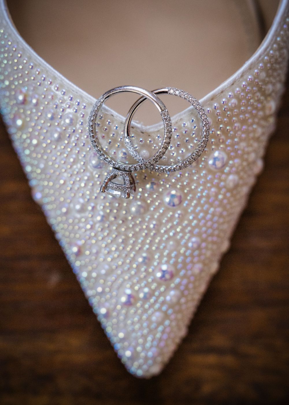 Pearl-encrusted bridal heel adorned with sparkling diamond engagement ring and wedding bands for an elegant wedding day.