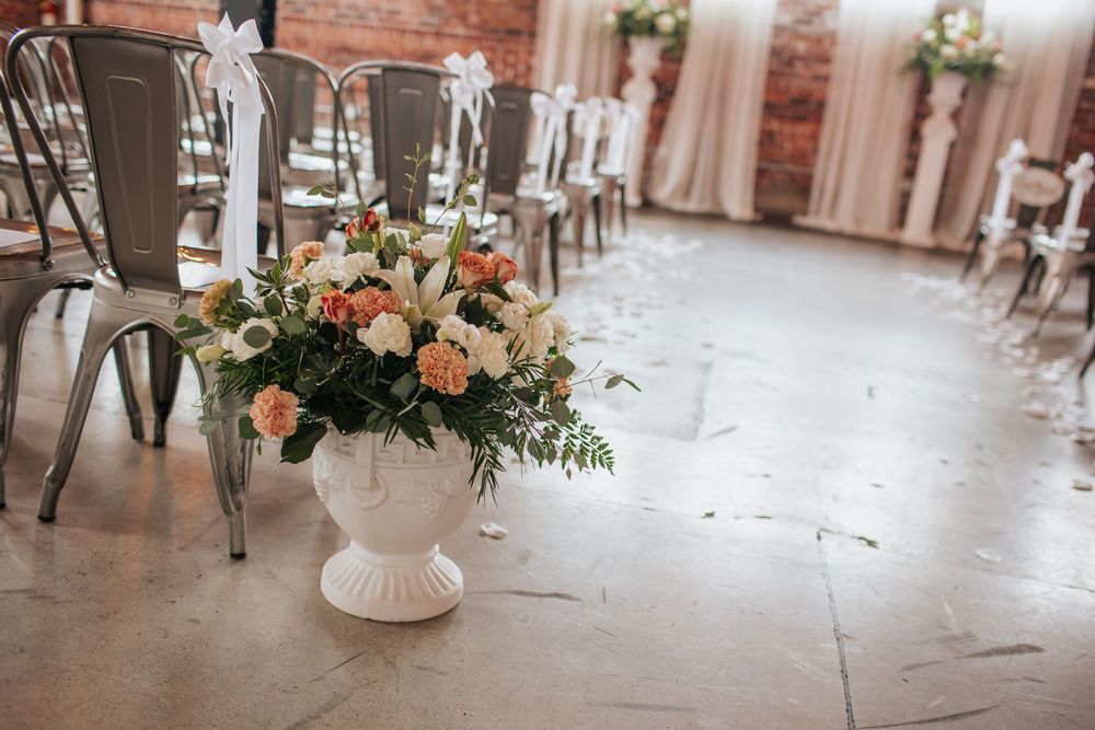 Elegant wedding reception venue with exposed brick walls, floral centerpieces, and industrial-chic decor details.
