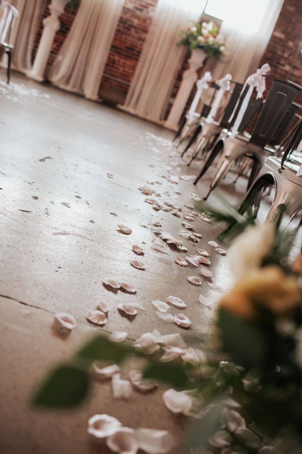 Paper airplanes scattered across a brick-lined hallway floor create an artistic path through an indoor space.