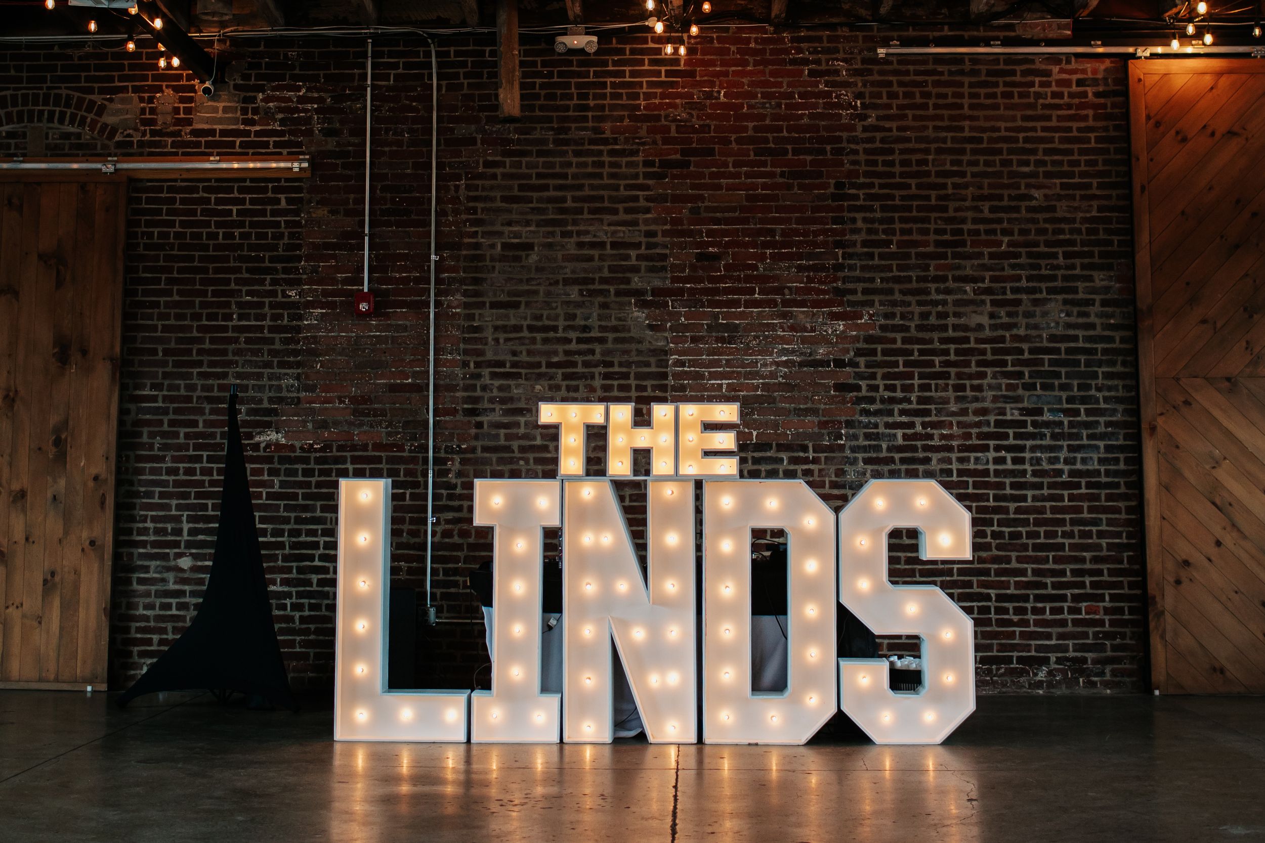 Exposed brick wall with illuminated text signs and industrial lighting creates a moody urban atmosphere.