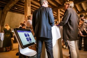 Een interactieve robot met Liantis-display staat prominent op de voorgrond tijdens een netwerkbijeenkomst