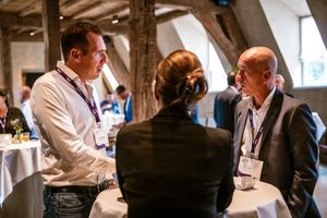 Drie mensen in gesprek tijdens een Liantis event in een rustieke ruimte met houten balken