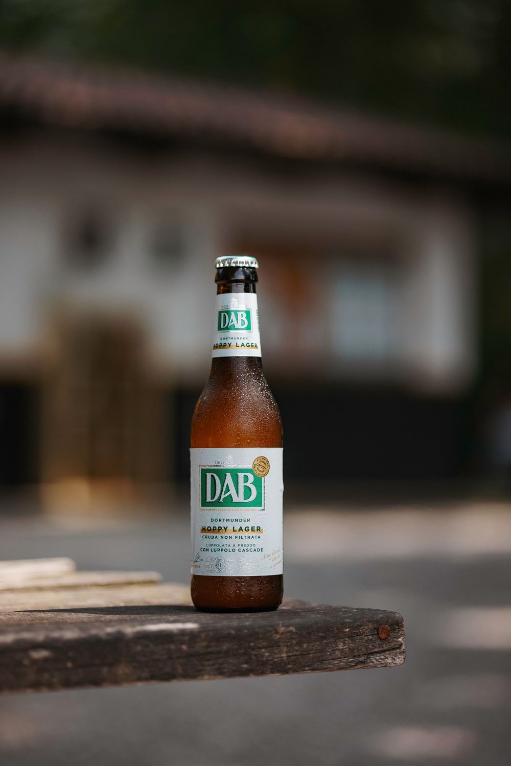 Four brown glass beer bottles sitting on a wooden surface with shallow depth of field and blurred backgrounds.