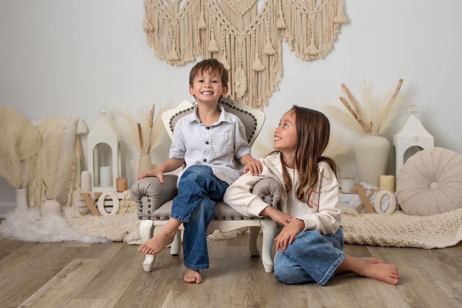 A person in white sits on a beige floor with macrame wall hangings and bohemian decor in the background.