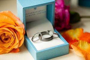 Wedding rings displayed in a light blue box with orange roses.
