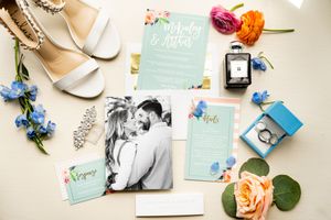 Wedding stationery and invitations in mint green and peach colors laid out on a white surface.