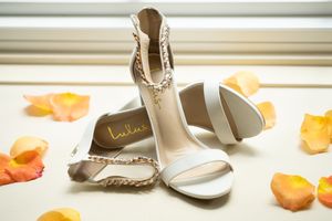 Wedding accessories including shoes and jewelry arranged on a white surface.