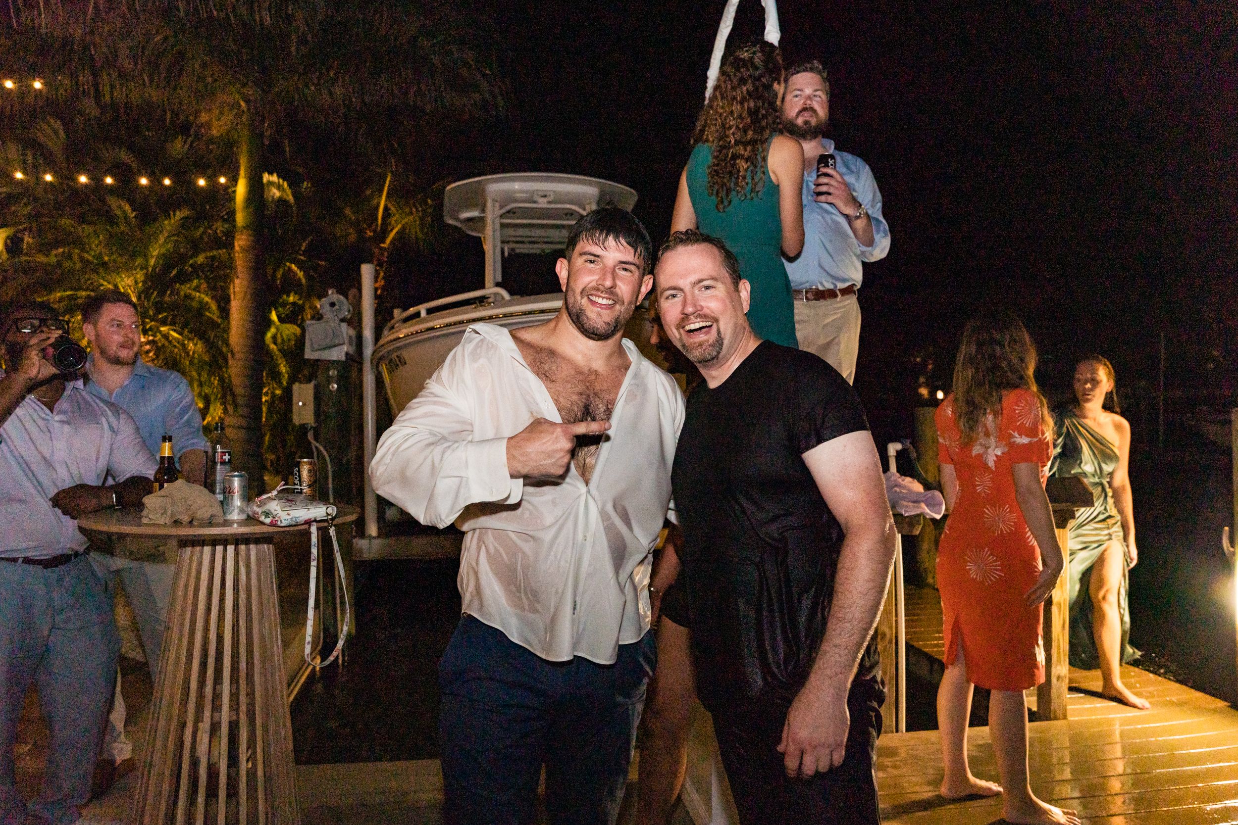 Guests mingling and socializing at an outdoor evening wedding reception with string lights.