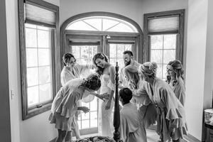 Wedding party getting ready in a bright room with large windows and elegant decor.