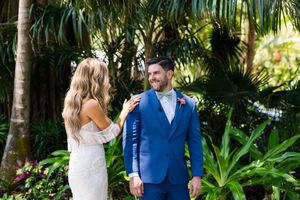 A wedding couple shares a first look moment in a lush tropical garden setting.