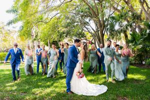 Wedding party and guests gathered for group photos on lush green garden lawn.