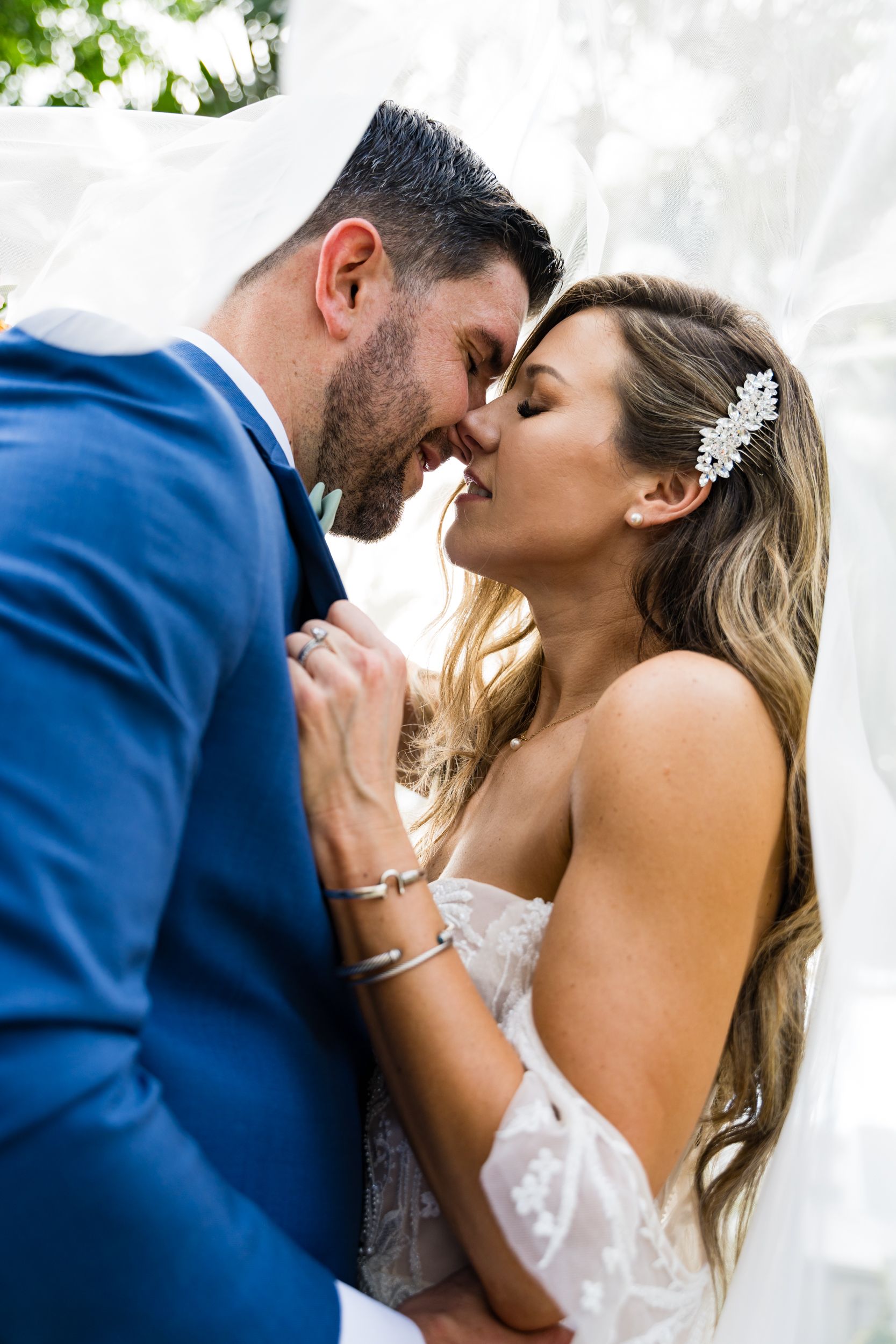 Romantic wedding couple shares intimate moments under a white veil in a series of close-up shots.