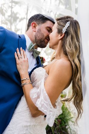 Romantic sequence of wedding couple sharing intimate kisses under a flowing veil in outdoor setting.