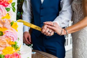 Close-up view of a couple holding hands during their wedding ceremony with colorful floral decorations.