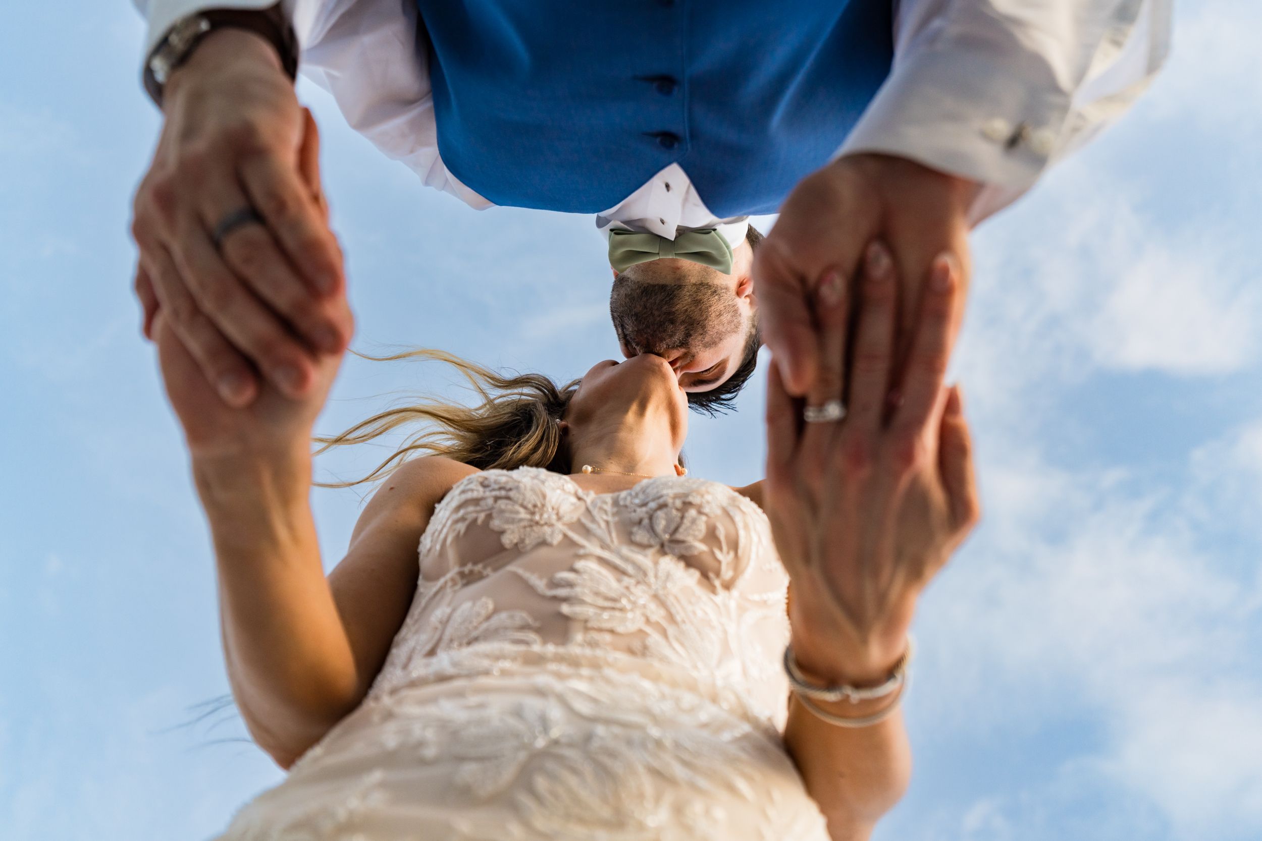 Close-up detail shots of a white lace wedding dress against a bright blue sky.