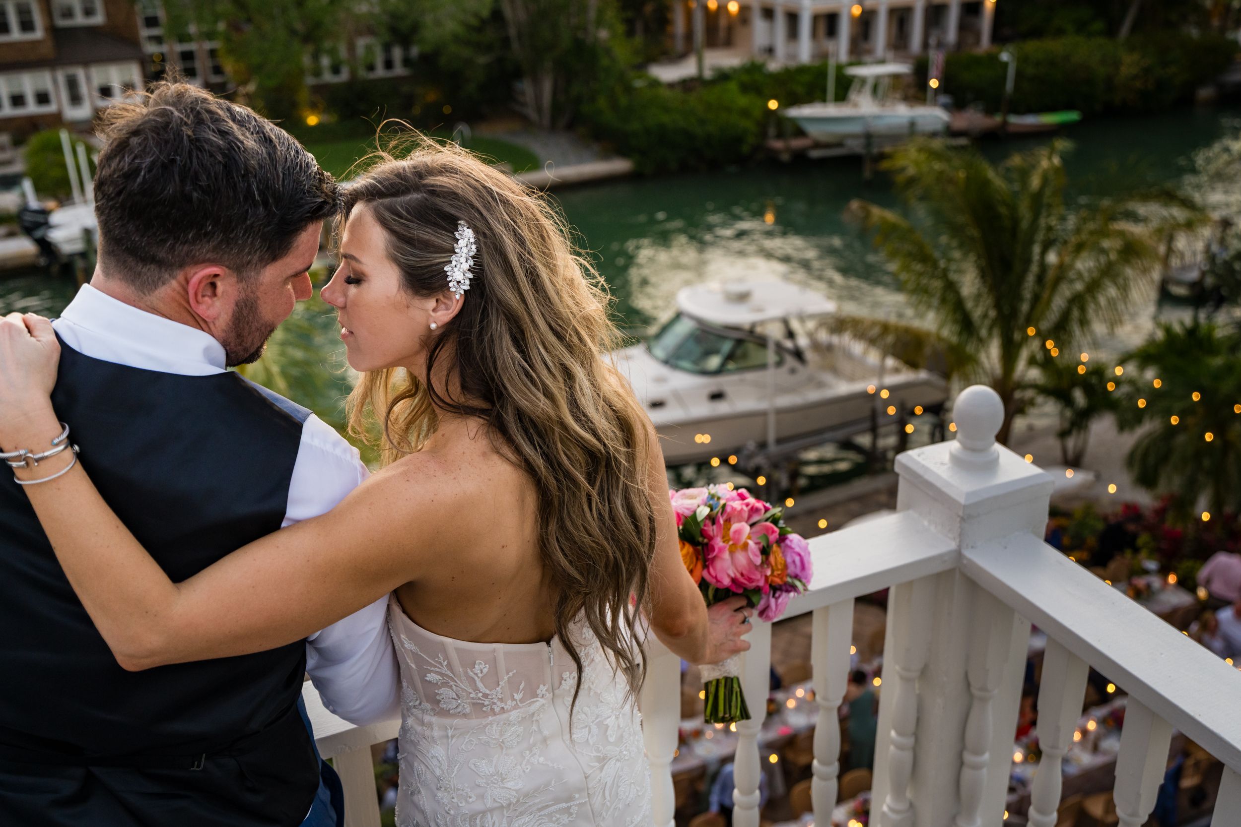 Wedding couple embraces on an elegant balcony with decorative railings.