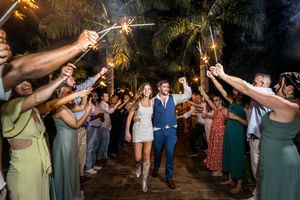 Sparklers light up the night as wedding guests celebrate on a dance floor.