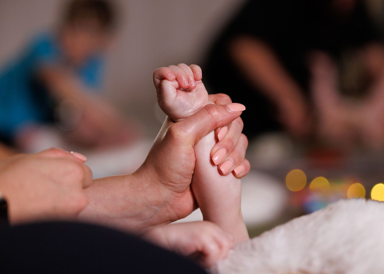 A close-up shot of tiny baby feet being gently held by adult hands against a soft background.