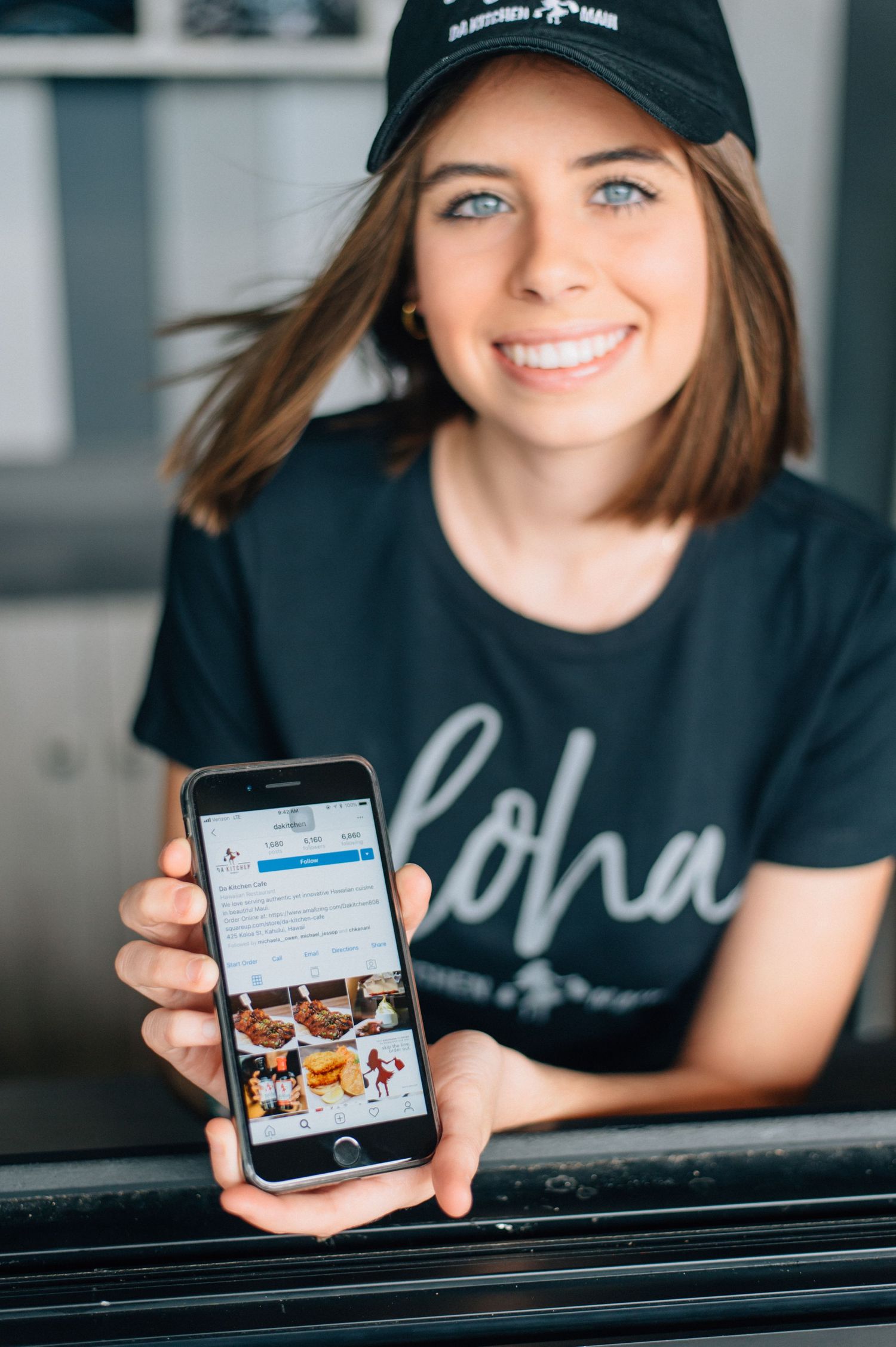 Restaurant worker displaying social media feed on smartphone.
