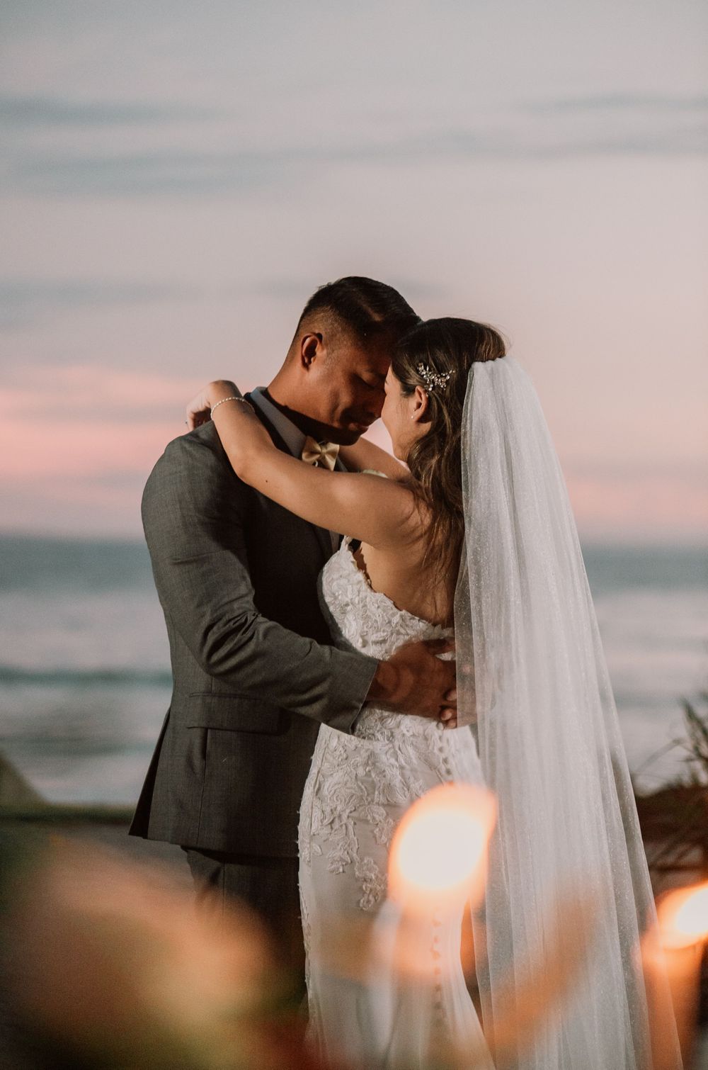 Intimate sunset wedding portraits with soft pink sky backdrop.