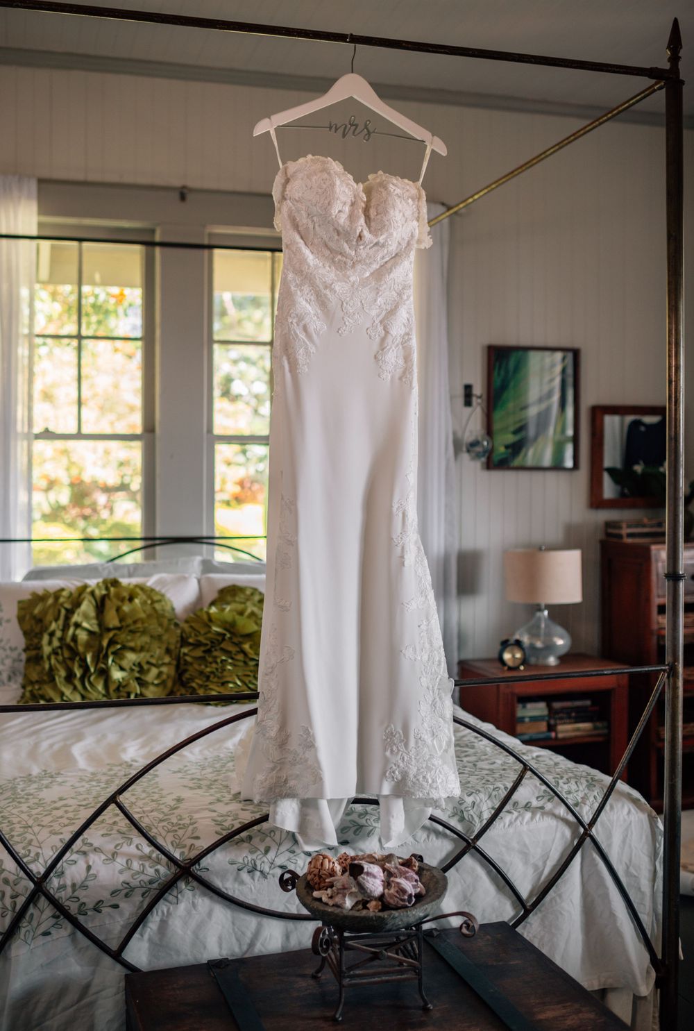 Wedding dress displayed on hanger against modern interior backdrop.