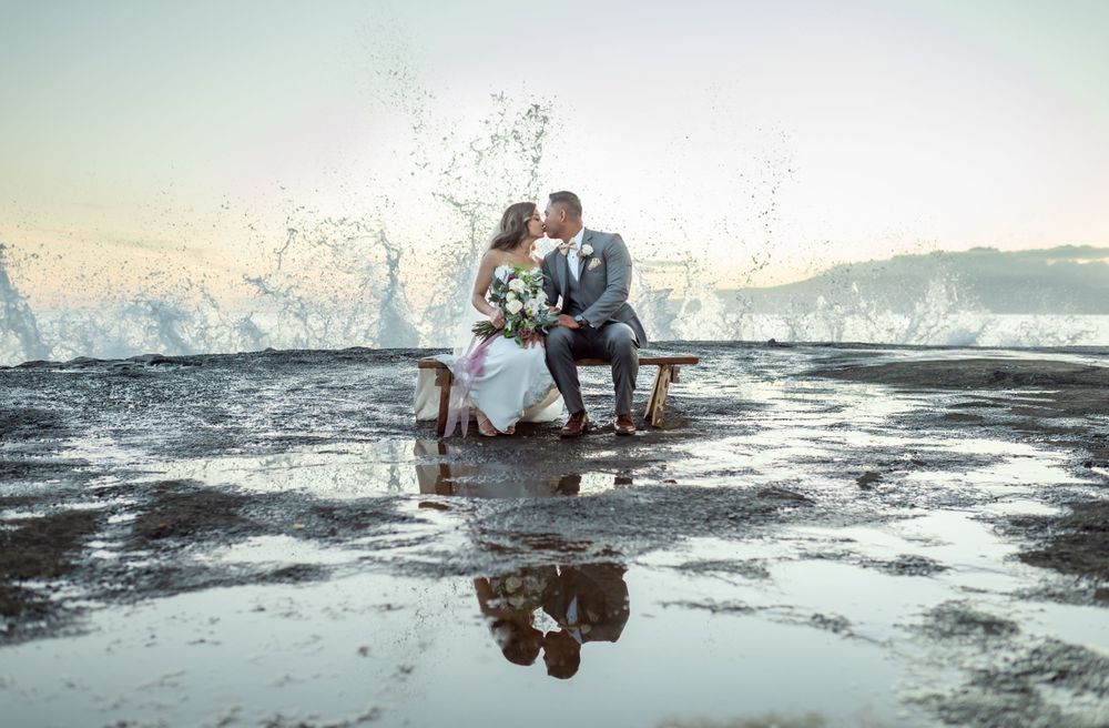 Romantic beach portraits with waves creating reflections at sunset.