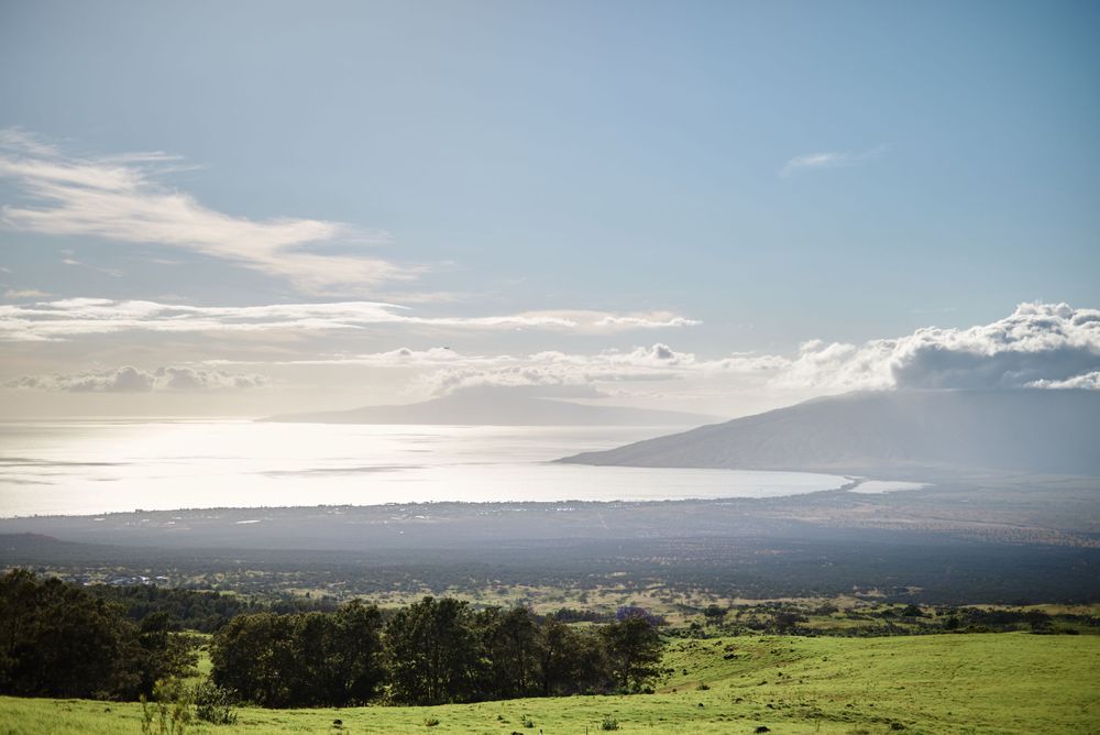 Sweeping panoramic view of Maui's coastline and mountains under a cloudy sky.