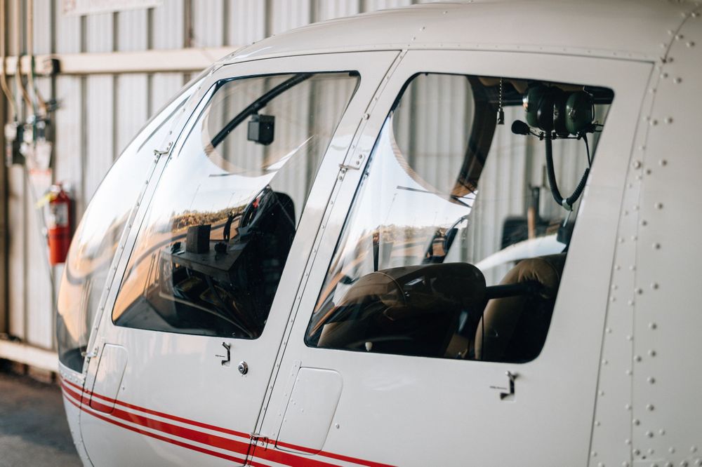 Side view of white aircraft with red trim parked in indoor hangar space.