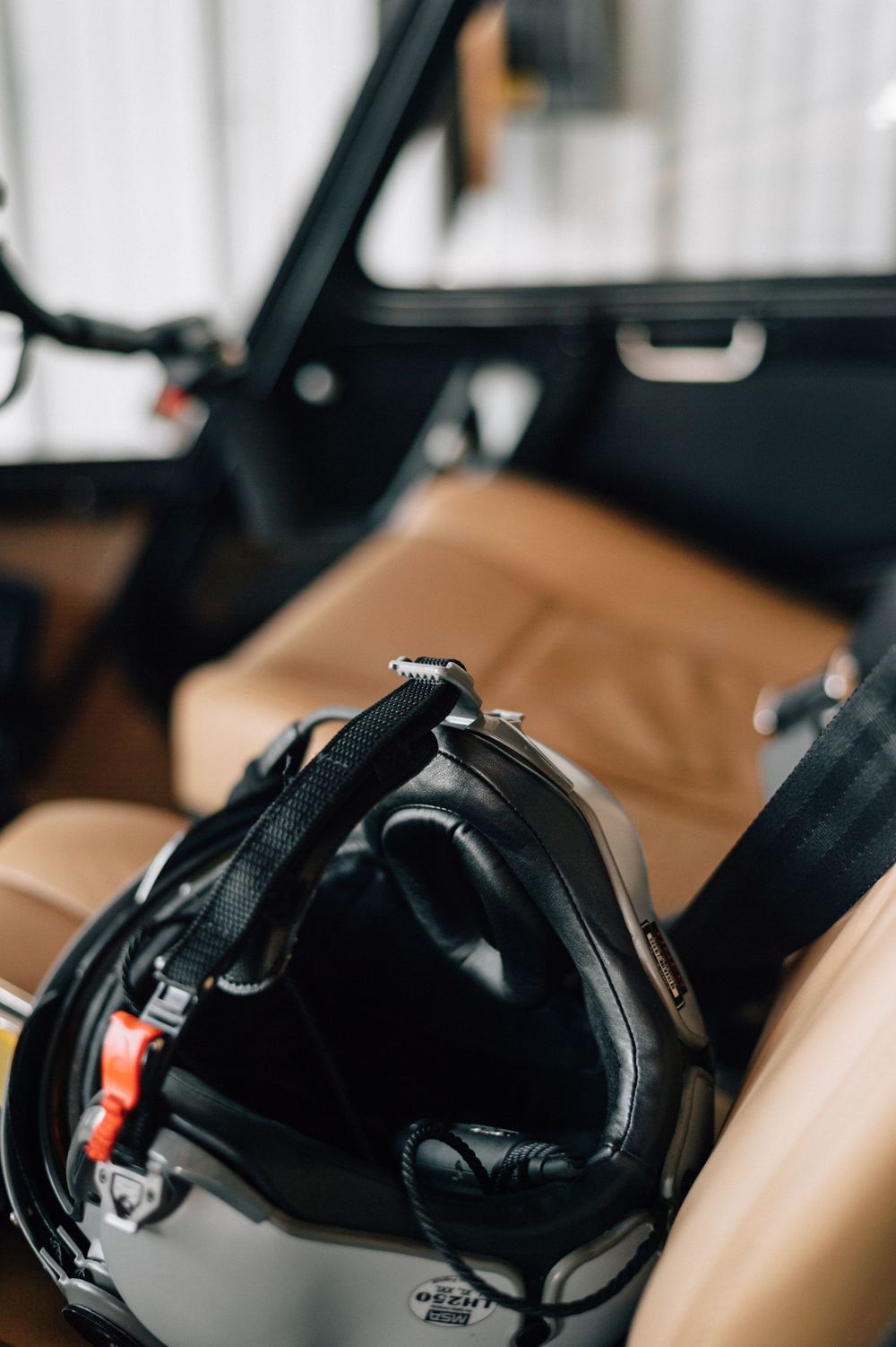 Black aviation headset resting on tan leather aircraft seat.