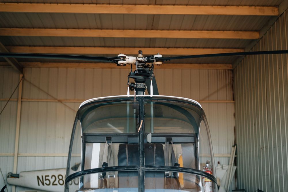 Row of aircraft stored in a metal hangar with overhead beams visible.