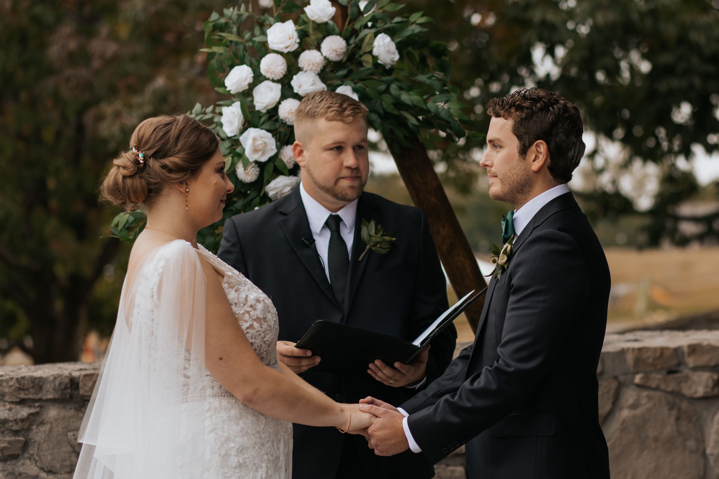 An emotional wedding ceremony moment with guests watching under autumn trees.
