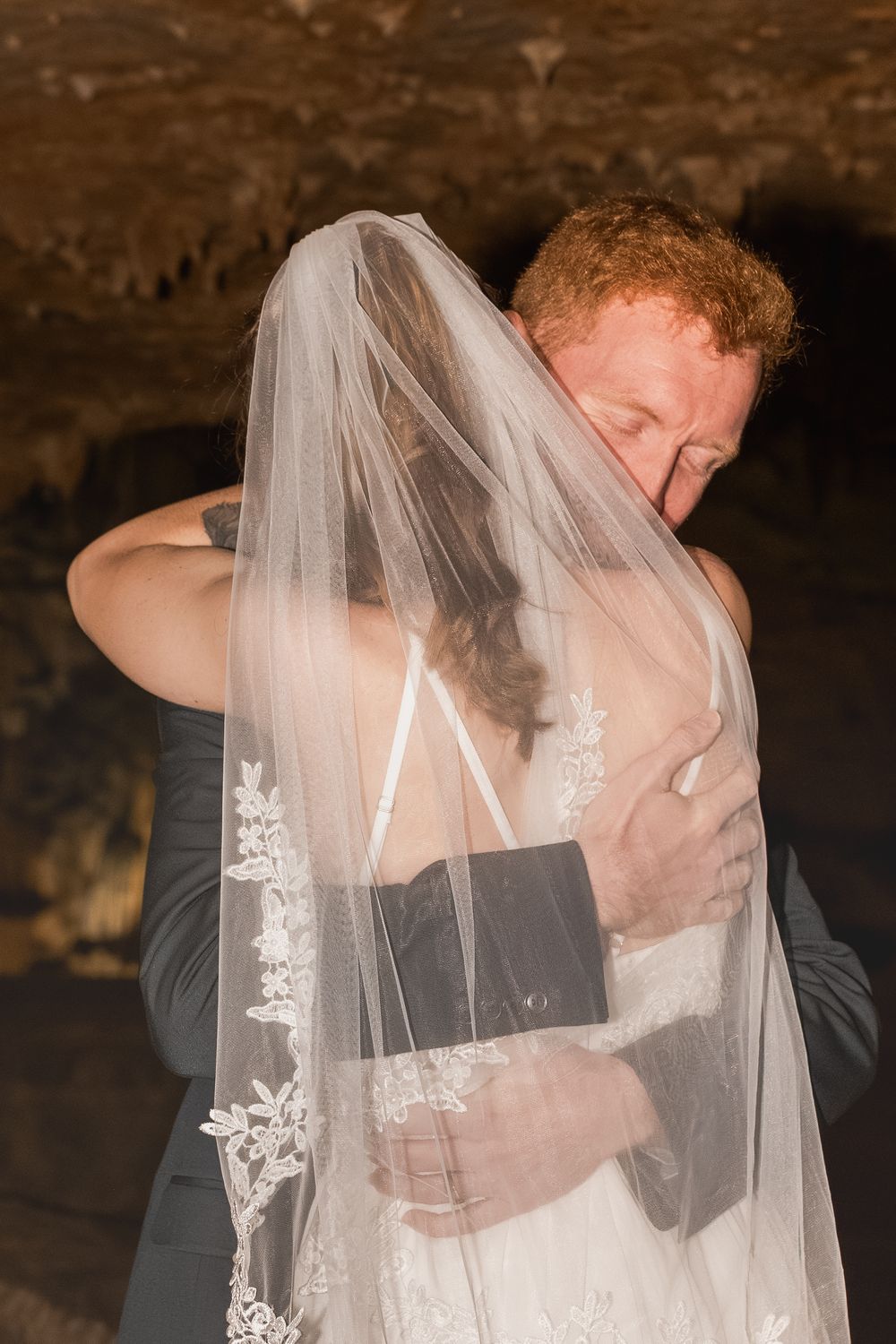 A romantic wedding moment captured as newlyweds share a kiss under a delicate lace-trimmed veil.