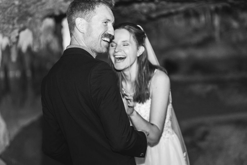 A couple shares a joyful moment together while dancing at their wedding celebration in black and white.