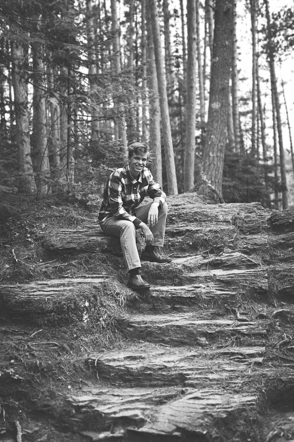 Black and white photo of a couple sitting together on a rocky forest path.