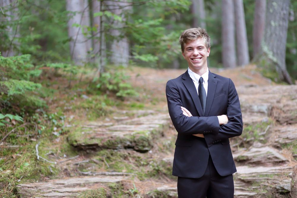 A formal portrait session in a scenic wooded forest setting with pine trees and natural lighting.