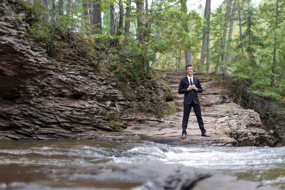 Professional photography session by a rocky stream in a lush forest setting.