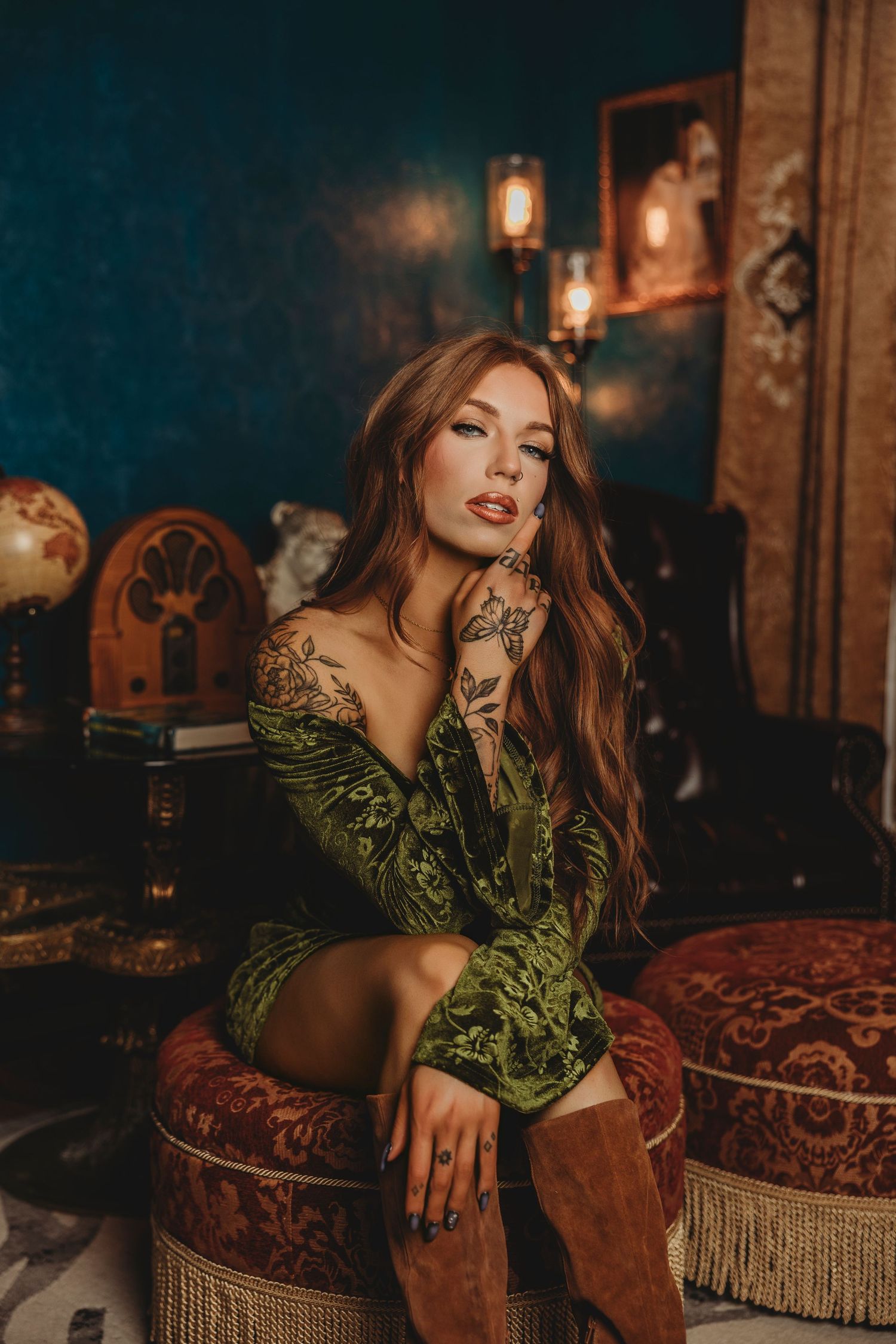 Fashion portrait in moody lighting featuring velvet dress and brown boots in vintage-style interior setting.