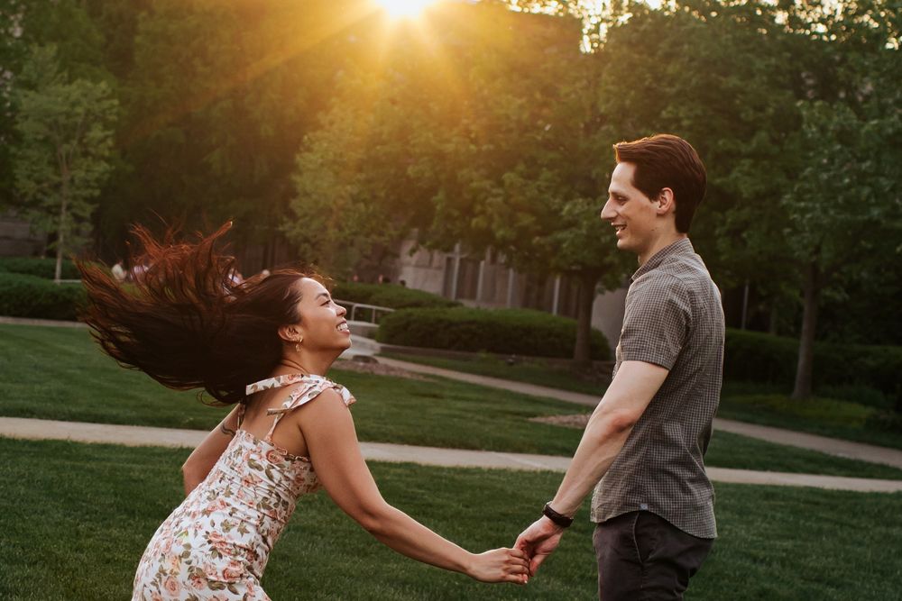 A couple dances together in a park at sunset creating romantic silhouettes against the golden light.