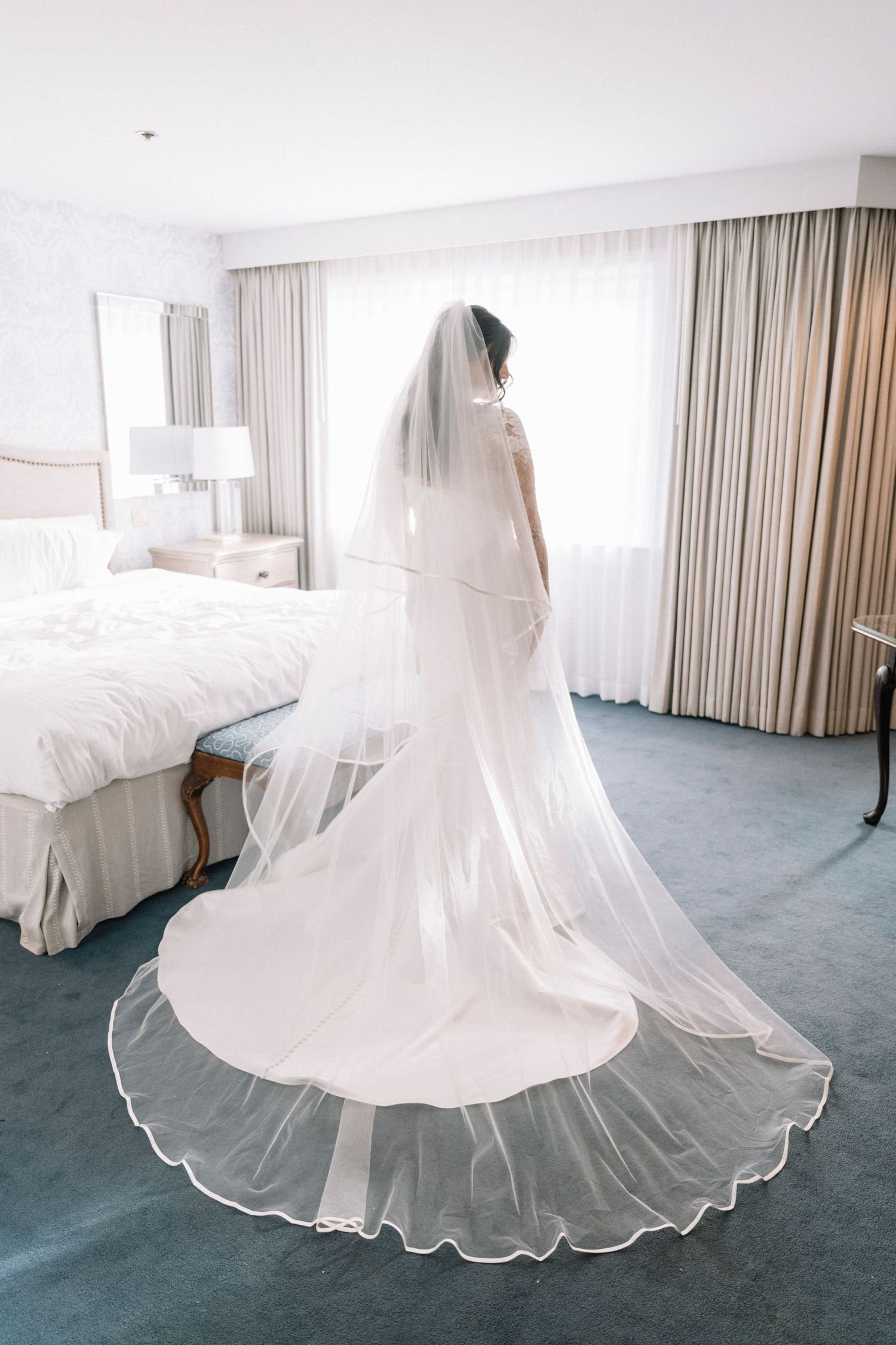 A flowing white wedding dress with layers of tulle skirt photographed in sequence on blue carpet.