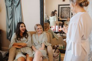 Bride getting ready in a bridal suite with bridesmaids helping with final touches of wedding preparation.