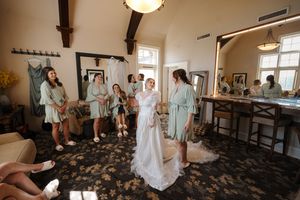 A collection of white wedding dresses displayed in a bridal boutique with stone flooring and natural lighting.