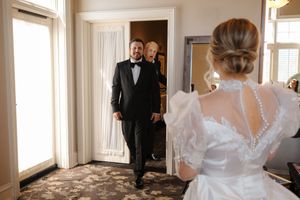 First look moment between a bride in a white lace gown and groom in tuxedo during their wedding day.