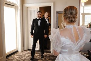 First look moment between a bride in a white lace gown and groom in tuxedo during their wedding day.